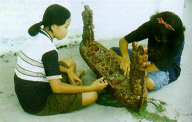 Girls playing on an elaborate congklak playing board